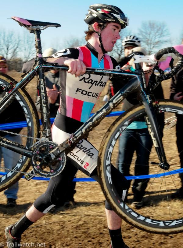 Zach McDonald (Rapha Focus) lifting his bike high over the barriers
