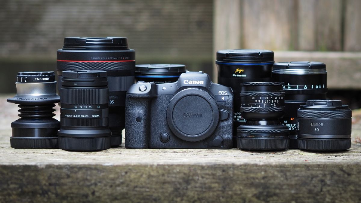 A Canon EOS R system camera body, sitting on a wooden outdoor surface, with a selection of Canon, Sigma, Laowa, Lensbaby, AstrHori and Zhongyi RF lenses