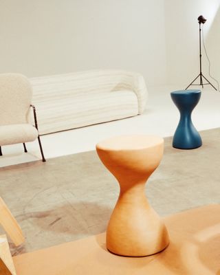 White sofa and chair and blue and wooden stools by Pierre Yovanovitch Mobilier