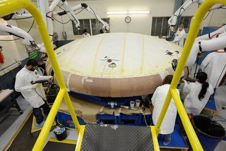 Technicians at Textron in Wilmington, Mass., apply Avcoat ablative material to the composite honeycomb structure attached to the Orion heat shield carrier structure.