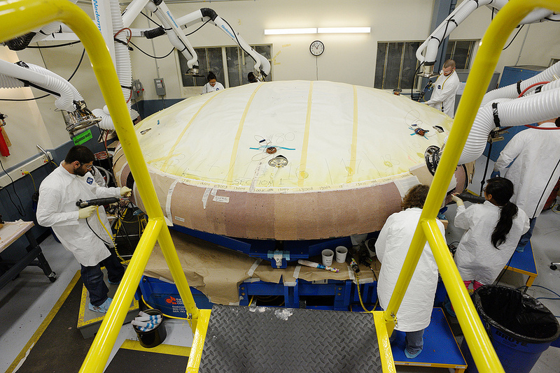 Technicians at Textron in Wilmington, Mass., apply Avcoat ablative material to the composite honeycomb structure attached to the Orion heat shield carrier structure.