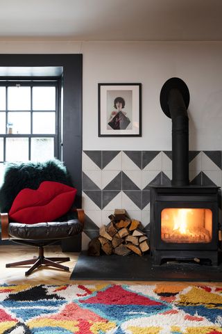 Black and white living room paint color idea with zigzagged wall tiles, fireplace and black chair with plush lip cushion