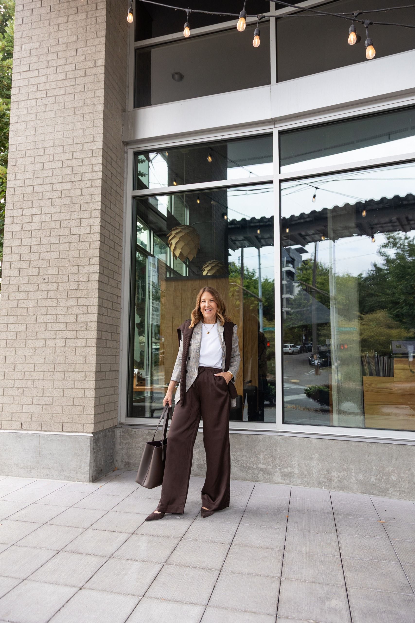 Sandy Koszarek wearing a cardigan, white tee, and satin trousers.
