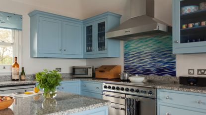 A light blue kitchen with a patterned backsplash