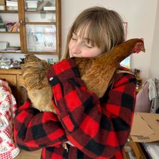Girl in red flannel shirt cuddling chicken