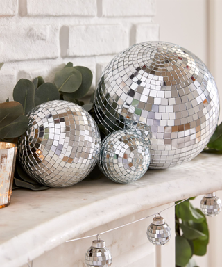 A set of disco ball Christmas ornaments on a mantel with eucalyptus