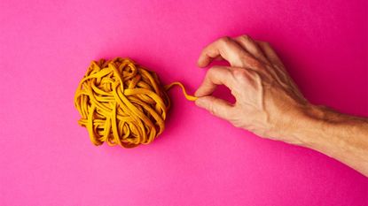 Hand pulling yellow thread from a tightly wound ball