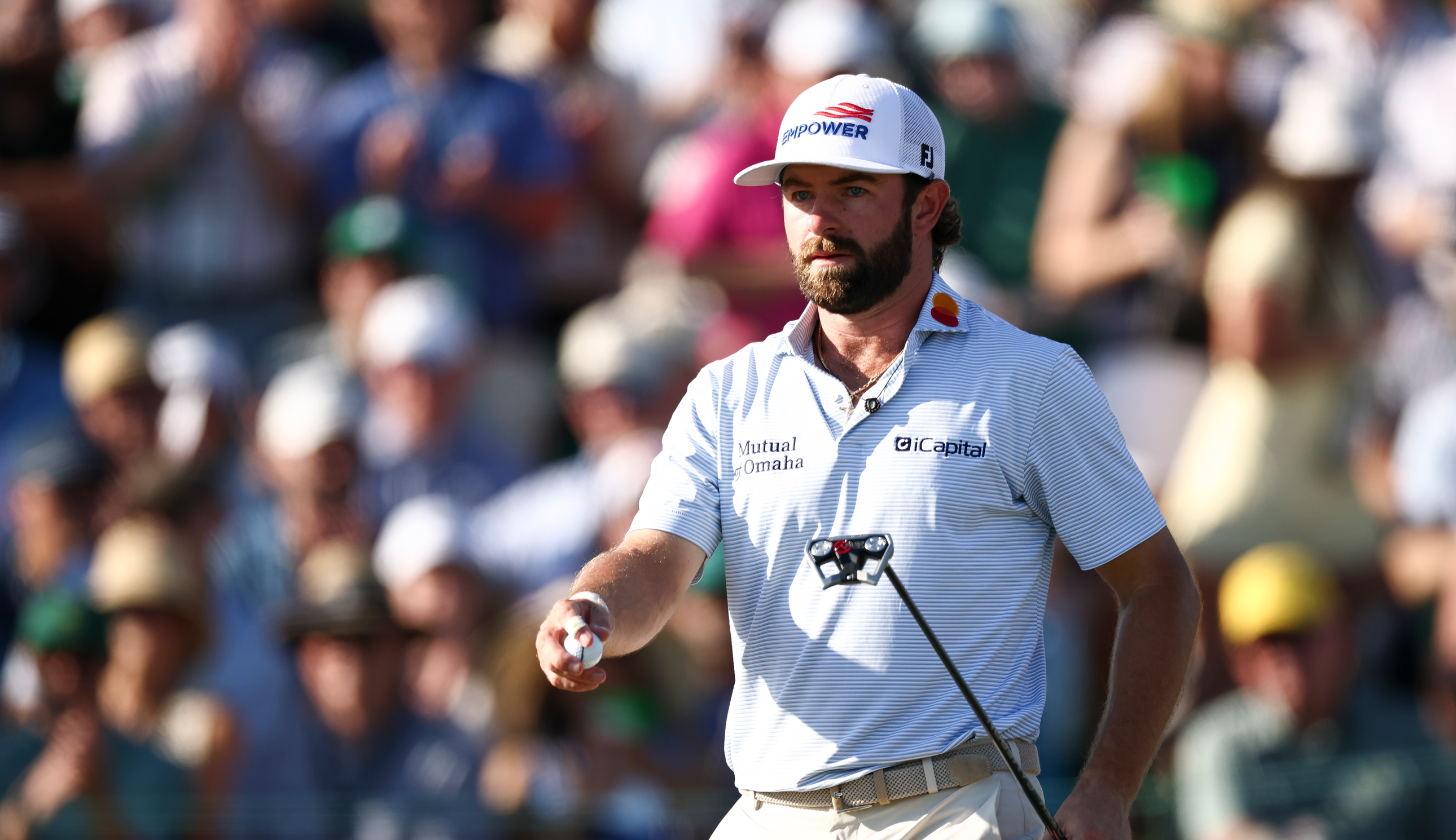 Cameron Young walks off the green holding a putter