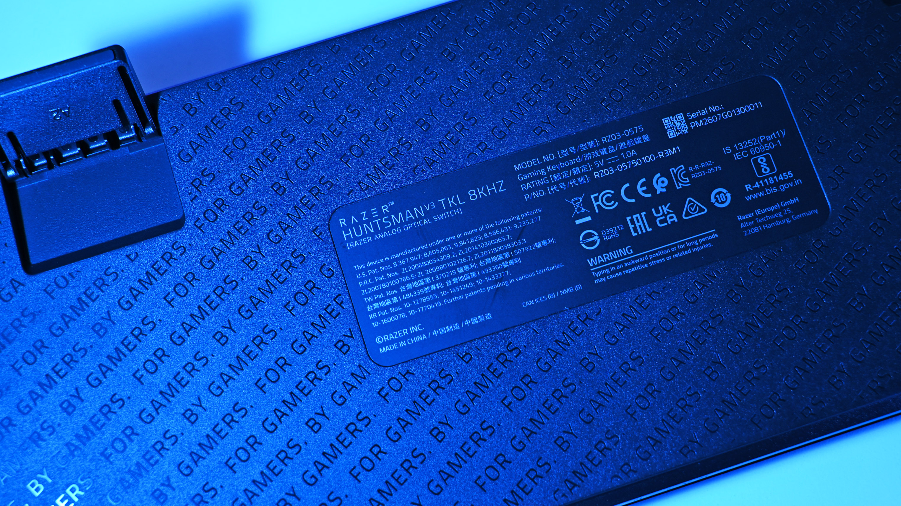 Close-up of the back of a Razer Huntsman V2 TKL keyboard with a focus on the label. The text &amp;ldquo;FOR GAMERS BY GAMERS&amp;rdquo; is visible in the background.