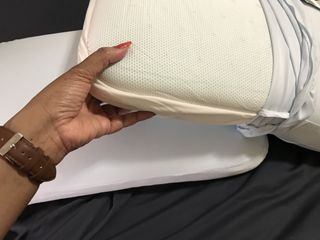 A hand holding the corner of an uncovered Casper Hybrid Snow Pillow