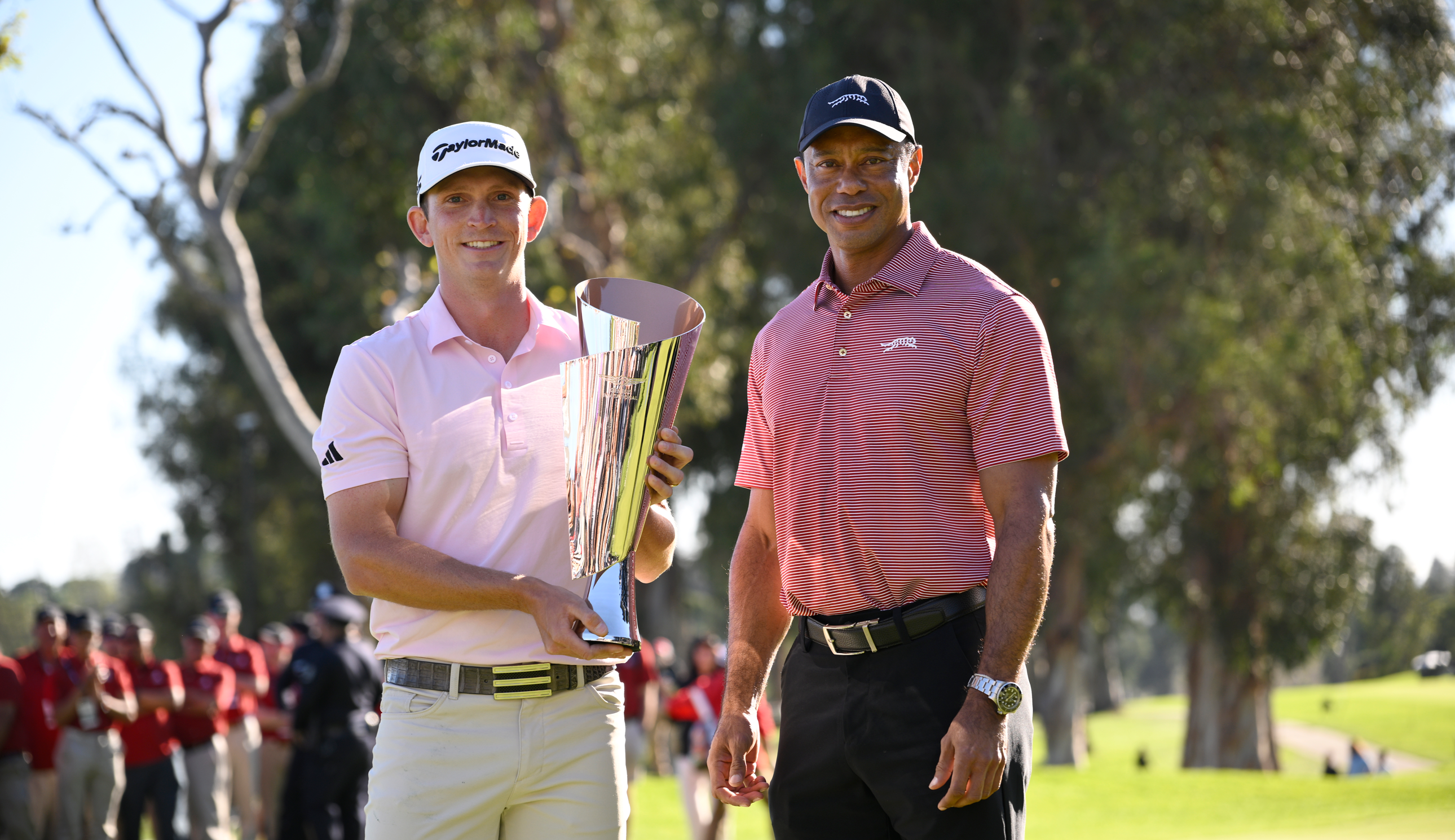 Jacob Bridgeman holds the Genesis Invitational trophy alongside Tiger Woods