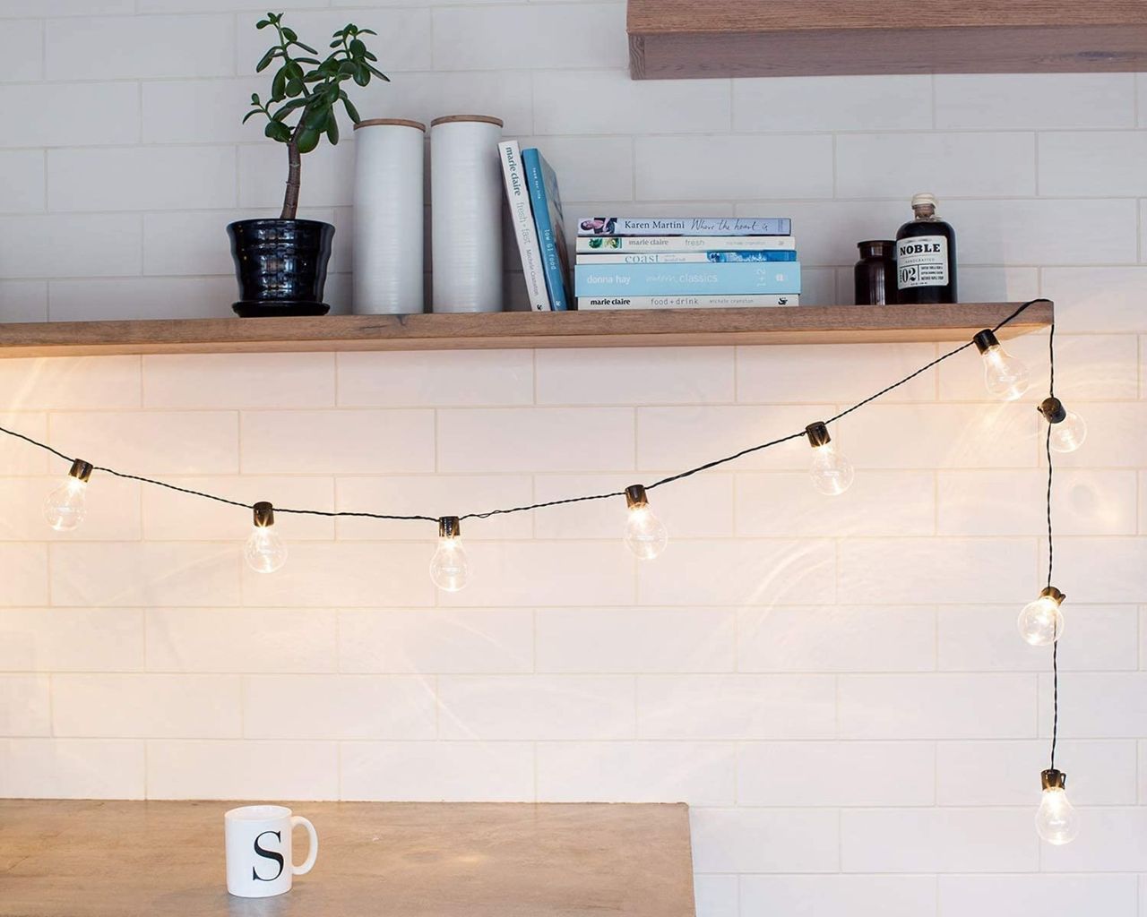 Lights4fun white festoon fairy lights draped in kitchen over open shelving