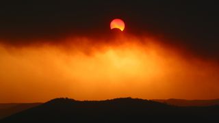 Partial solar eclipse on December 4, 2002 through thick plume of bushfire smoke over Broken Bay, NSW, Australia