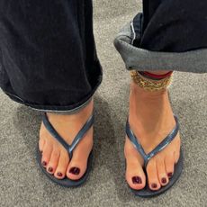 A woman wearing navy flip flops with a burgundy pedicure