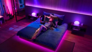 A man lying on a bed listening to Spotify with Philips Hue lights dancing to the music