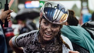 Kate Courtney covered in mud in rainbow jersey