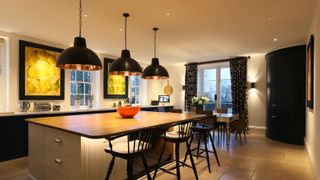 kitchen lit with downlights and pendants over large kitchen island
