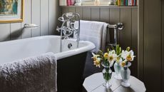 A wood paneled bathroom area featuring an antique style tub with polished nickel hardware