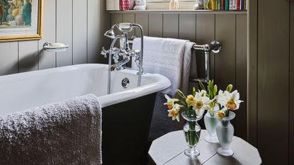 A wood paneled bathroom area featuring an antique style tub with polished nickel hardware