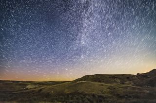 a streak of light crosses the night sky, dimming periodically as it does