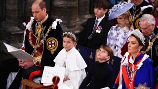 From left to right: Prince William looking down at a program, Princess Charlotte looking to her left, Prince Louis looking upward and Kate Middleton looking forward at King Charles' coronation.