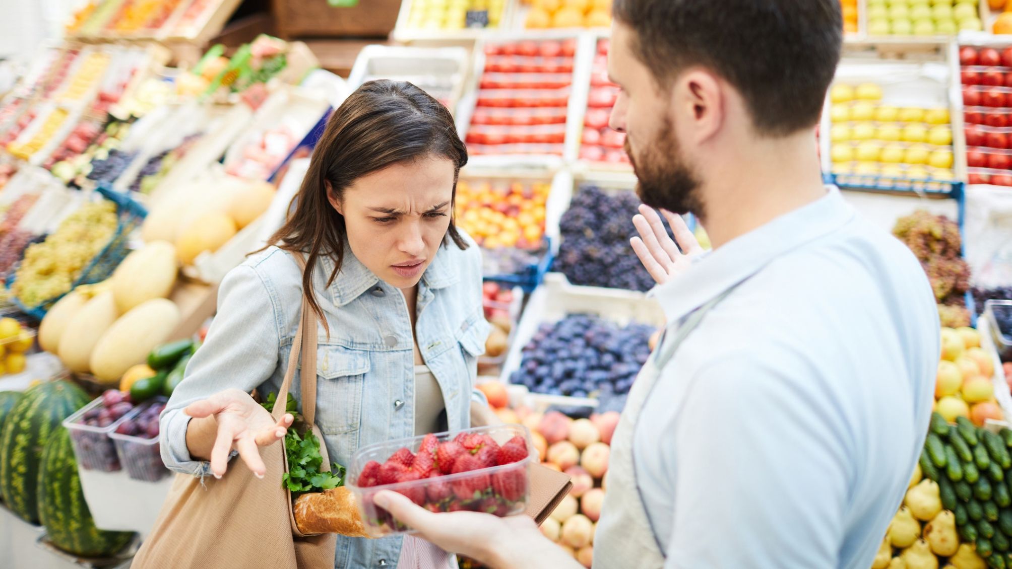 A woman is looking at poor quality produce a man is showing her