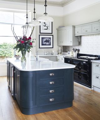 A kitchen with a large blue island with drawers and corner cupboards illustrating kitchen cupboard storage ideas.