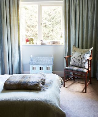 Gender neutral kids bedroom ideas with a dolls house, pale blue drapes and tartan blankets.