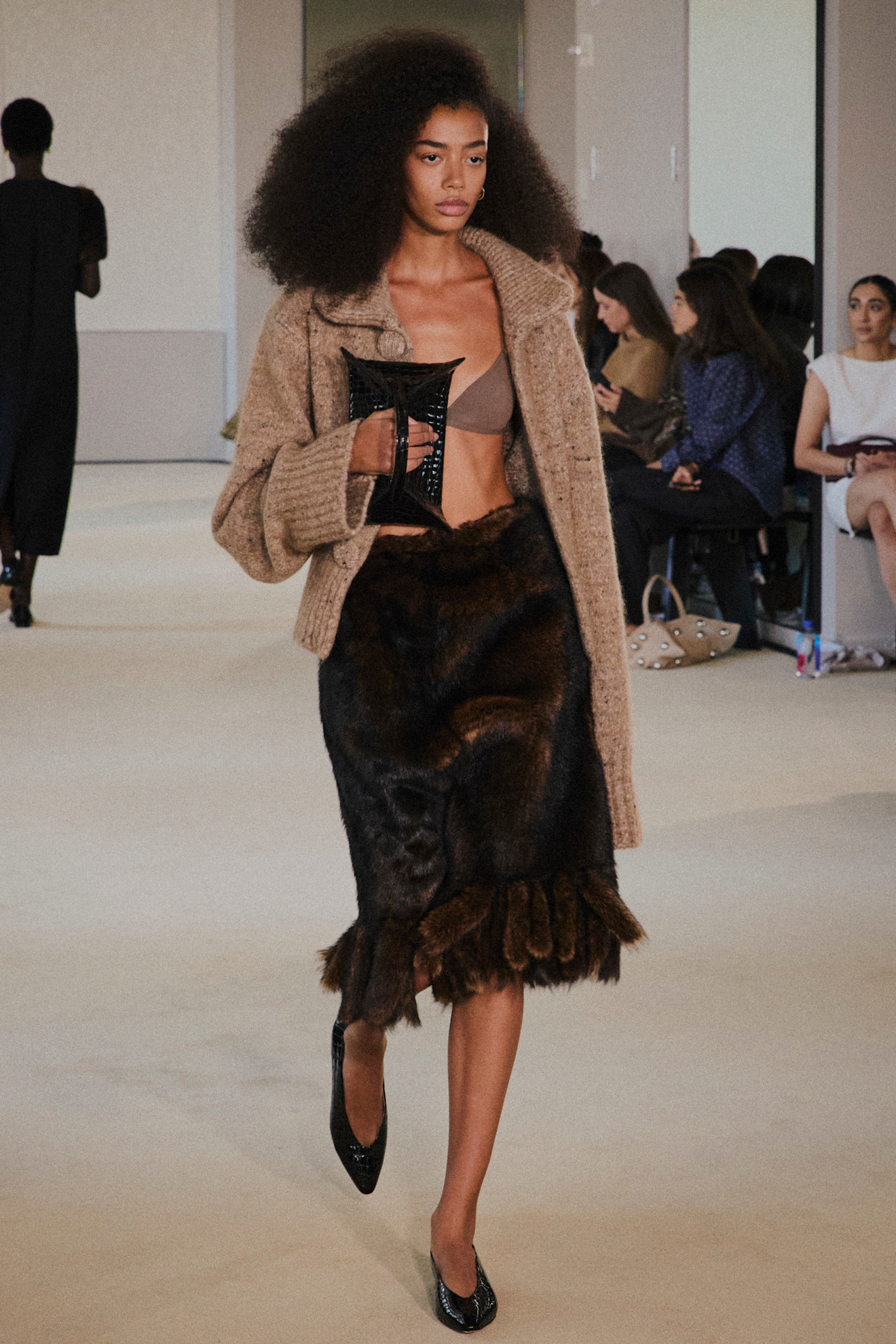 A model at the spring/summer 2026 show for Altuzarra wearing a chunky cardigan, bralette, and fur skirt.