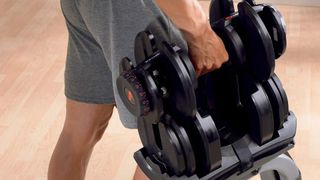 Person picking up the Bowflex Selecttech dumbbell