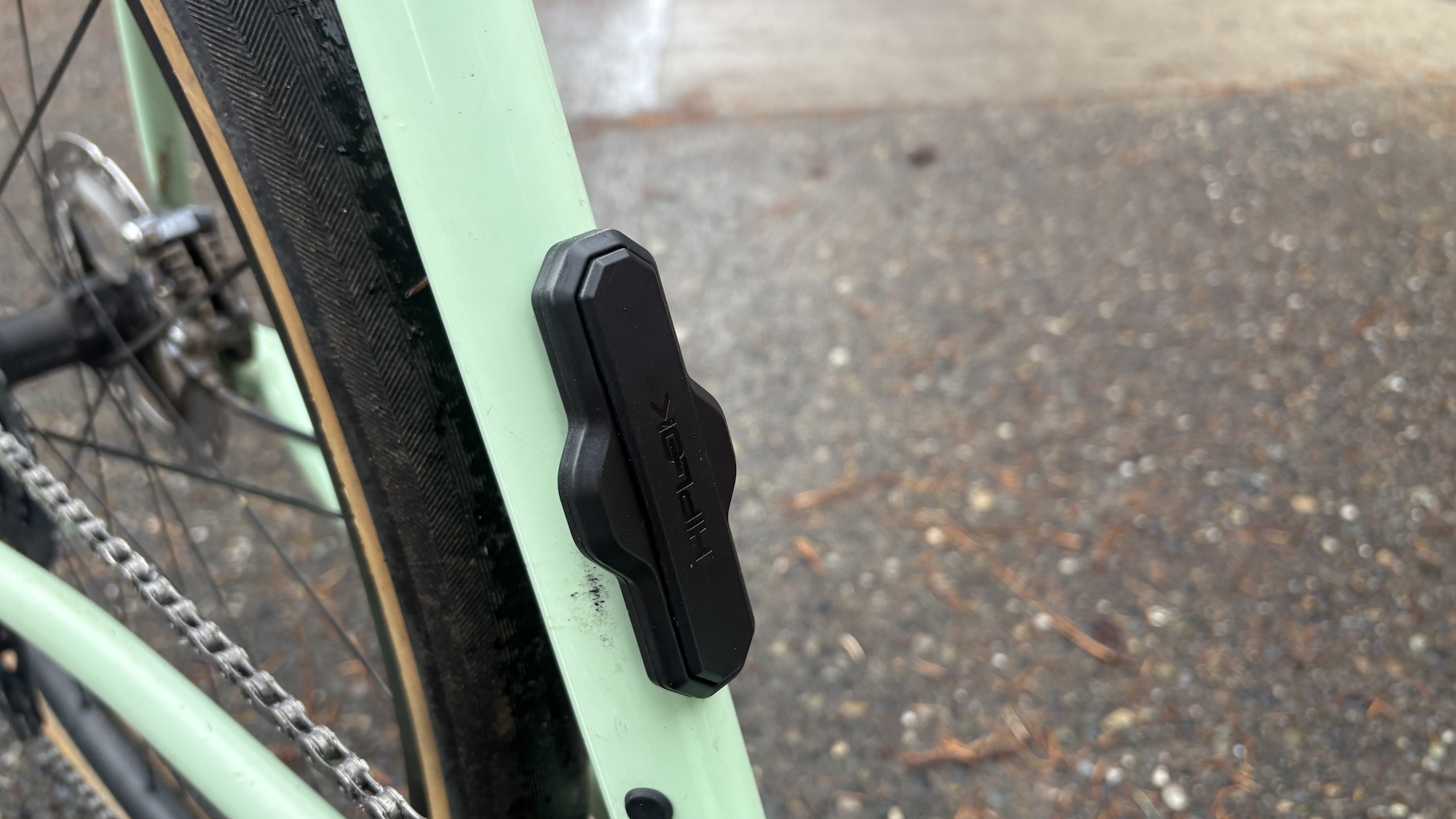 The hiplok track airtag holder mounted to the seat tube bottle cage mount of a mint coloured Rock Lobster gravel bike. 