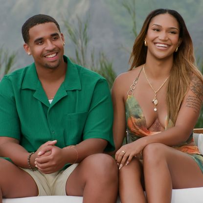 Mikey Bivens and Sydney McGregor sit together on a couch smiling in a still from temptation island season 2