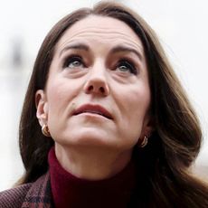 Princess Kate wearing a maroon sweater and coat looking up