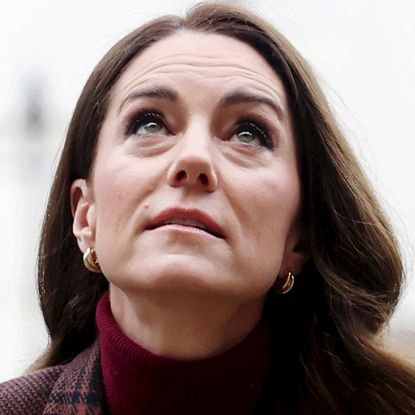 Princess Kate wearing a maroon sweater and coat looking up