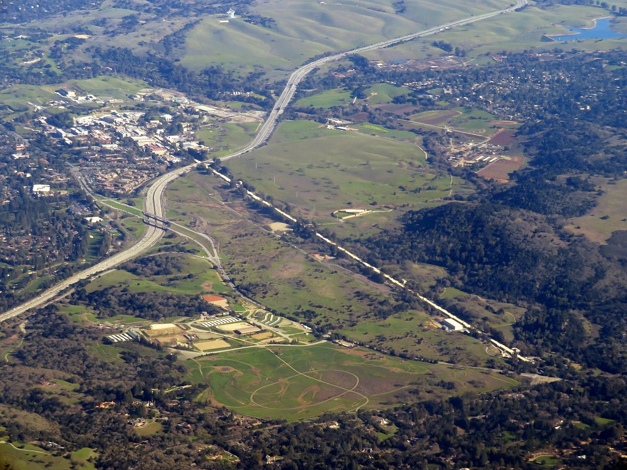 an aerial view of a green hillside with a brown line running through it