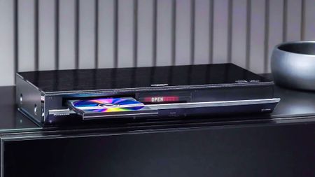 The Panasonic DP-UB8204K UHD Blu-ray player atop a credenza with its disc tray open