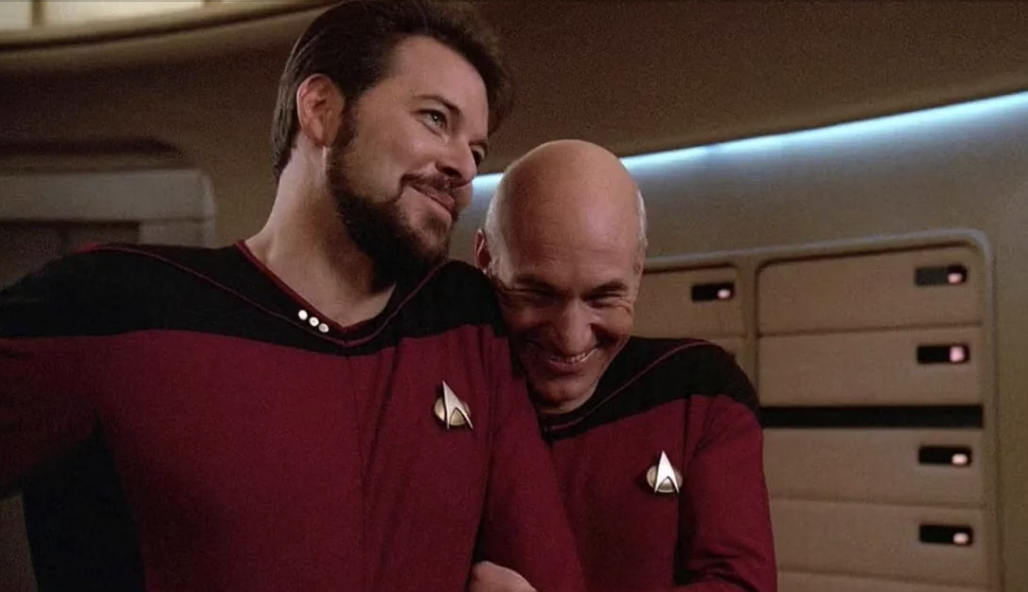 two men laughing together on a sci-fi tv set