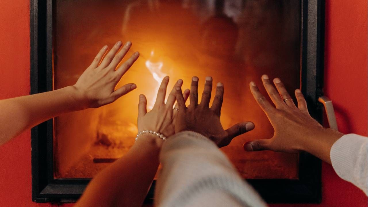 Four hands warming themselves in front of a fire