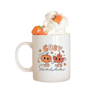 A fall mug with a leaf illustration and whipped cream on top
