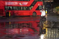 A cyclist rides in front of a red London bus