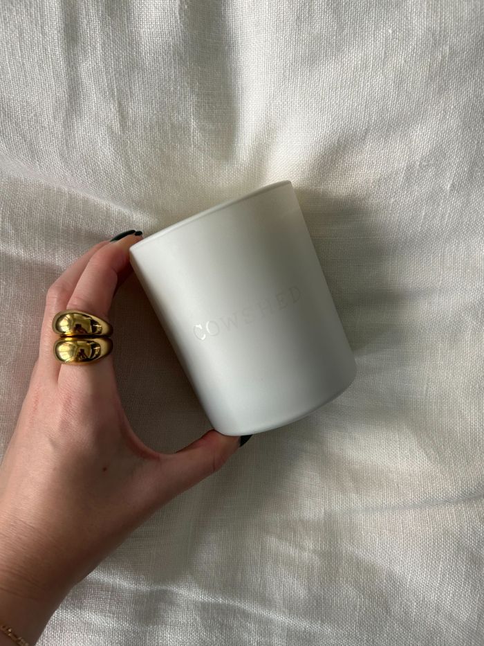 Junior beauty editor Grace Lindsay holding one of the best autumn candles against a white linen background