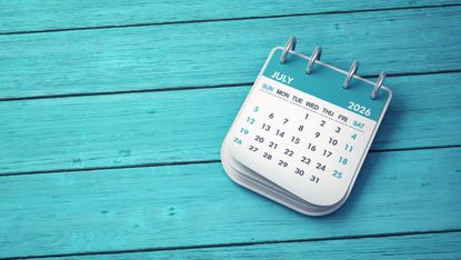 Desk calendar showing July 2026 against turquoise wooden background.