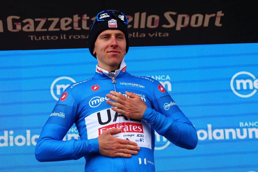 Pink jersey Team UAE's Slovenian rider Tadej Pogacar celebrates the best climber's blue jersey on the podium after winning the 15th stage of the 107th Giro d'Italia cycling race, 222km between Manerba del Garda and Mottolino on May 19, 2024. (Photo by Luca Bettini / POOL / AFP)