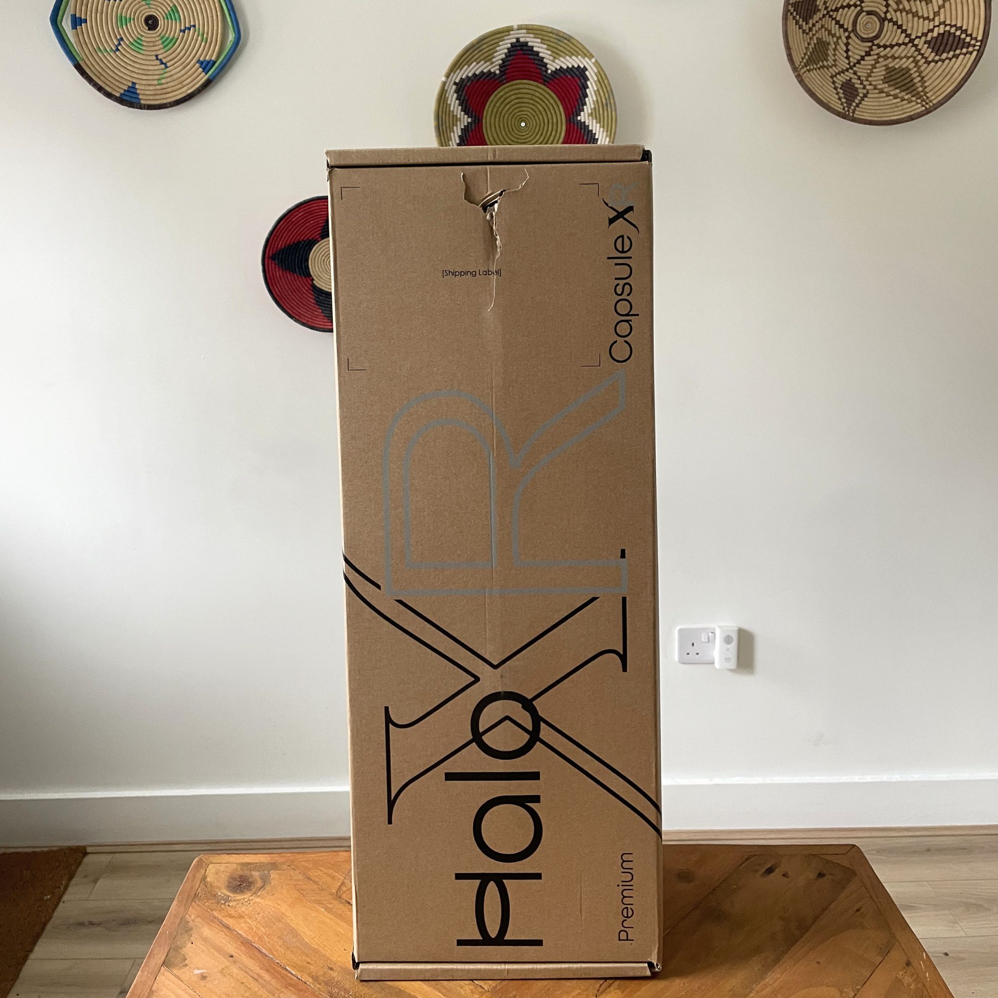 Halo Capsule XR Cordless Vacuum Cleaner box sitting on a wooden table in front of a white painted wall