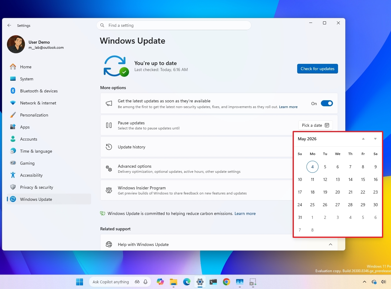 Windows Update settings page on a computer screen shows updates are up to date. A May 2026 calendar is open, highlighting May 4th.