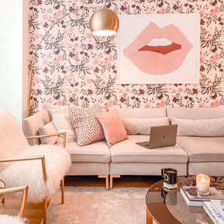 Soft blush living room scheme with modern floral wallpaper, playful wall art, cocoon floor lamo, and tactile seating.