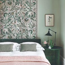 A green-painted bedroom with a floral wall tapestry