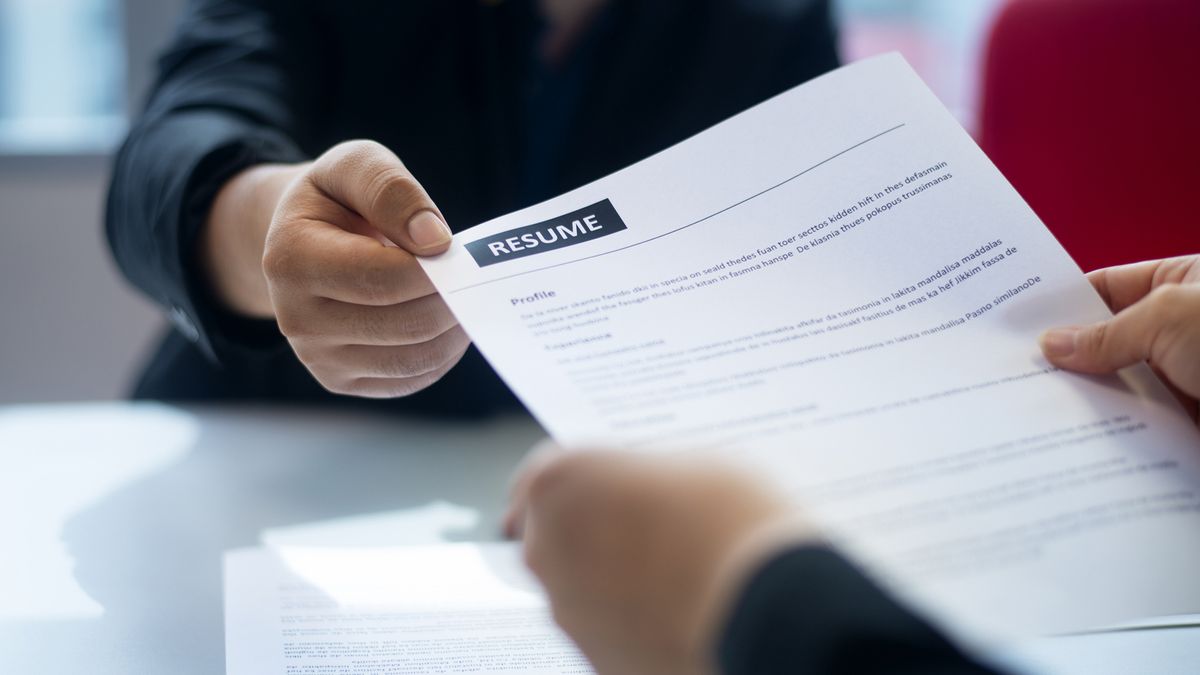 Person handing printed resume to another person