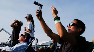 Amos Yew, right, uses a lens on an iPhone to record video in the first stages of the total solar eclipse Monday August 21, 2017 in Madras, Oregon