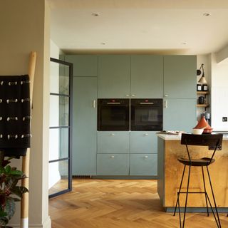 Green kitchen with slab doors and bronze island